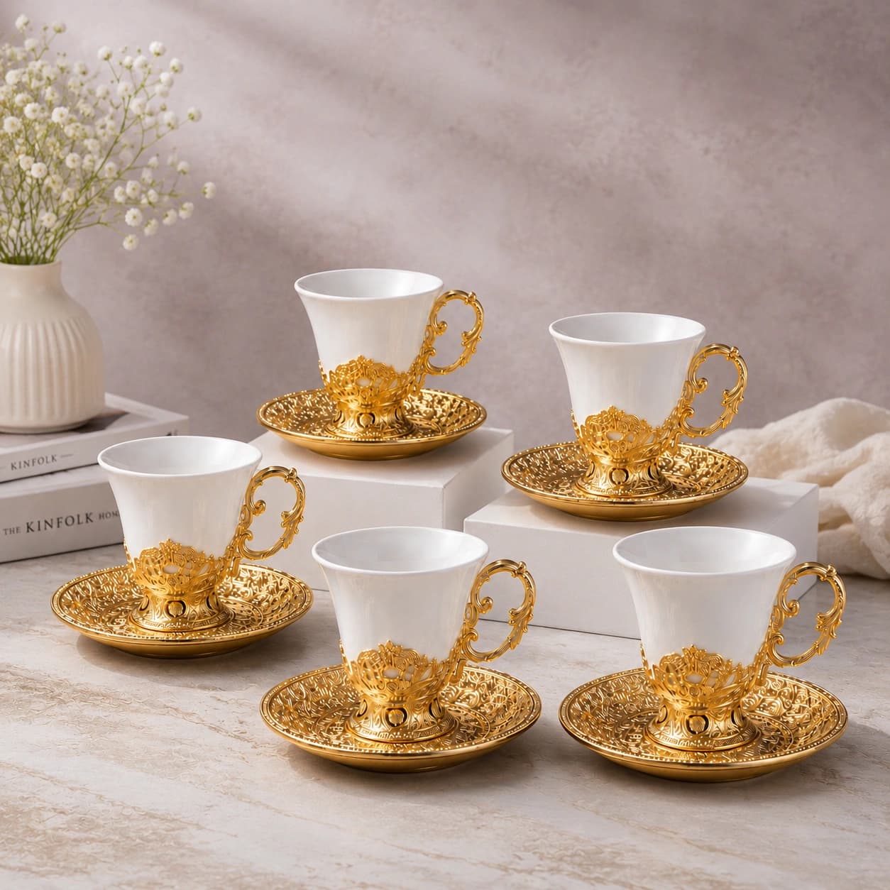 White porcelain cups with ornate gold saucers arranged on display blocks