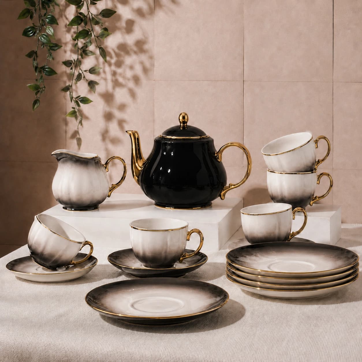 Black ceramic teapot with cups and plates accented with gold trim